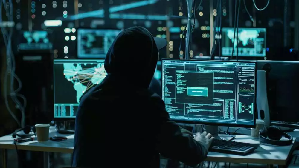 Teenage Hacker Working with His Computer Infecting Servers and Infrastructure with Malware. His Hideout is Dark, Neon Lit and Has Multiple displays.